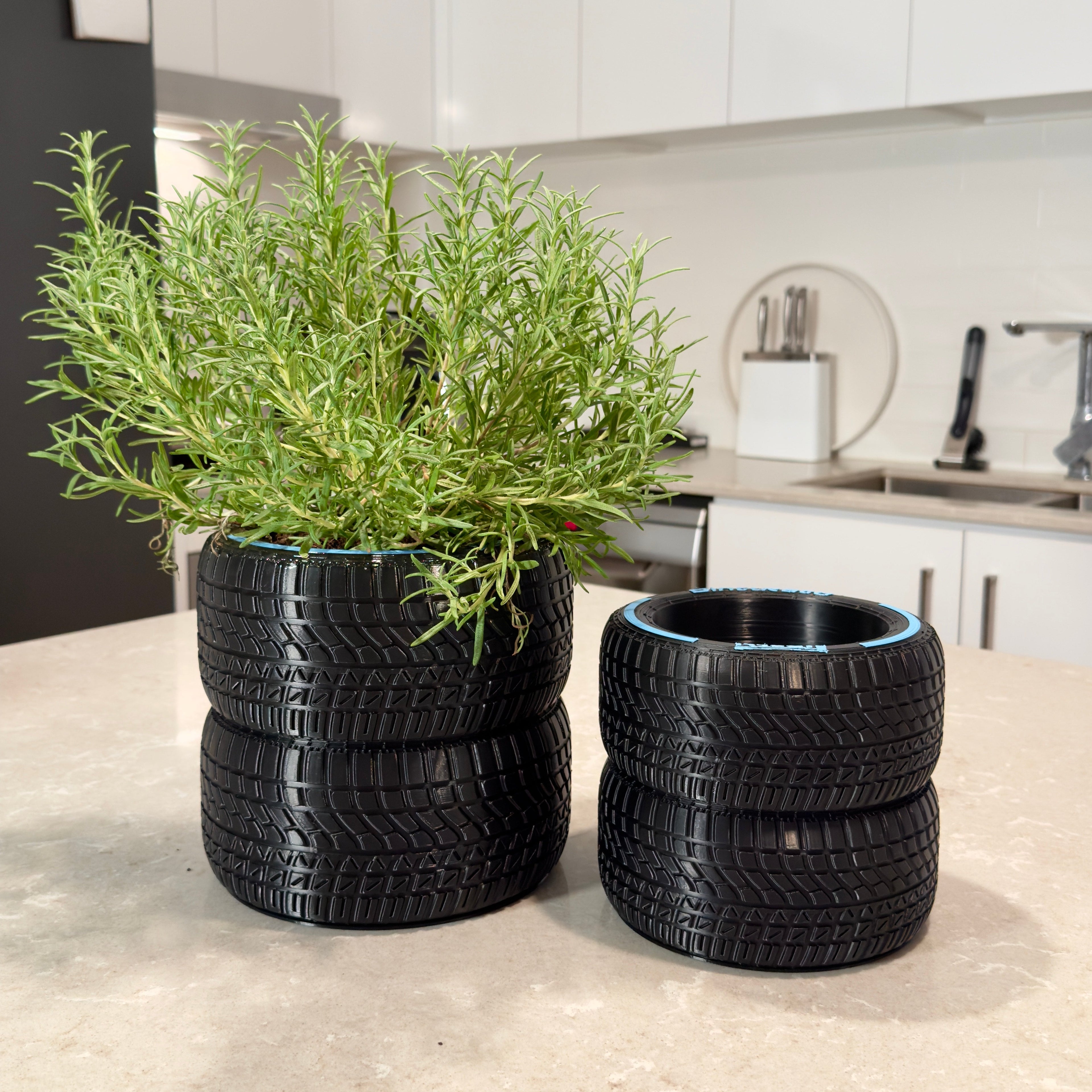 Two tire planters with green plants on a kitchen counter.